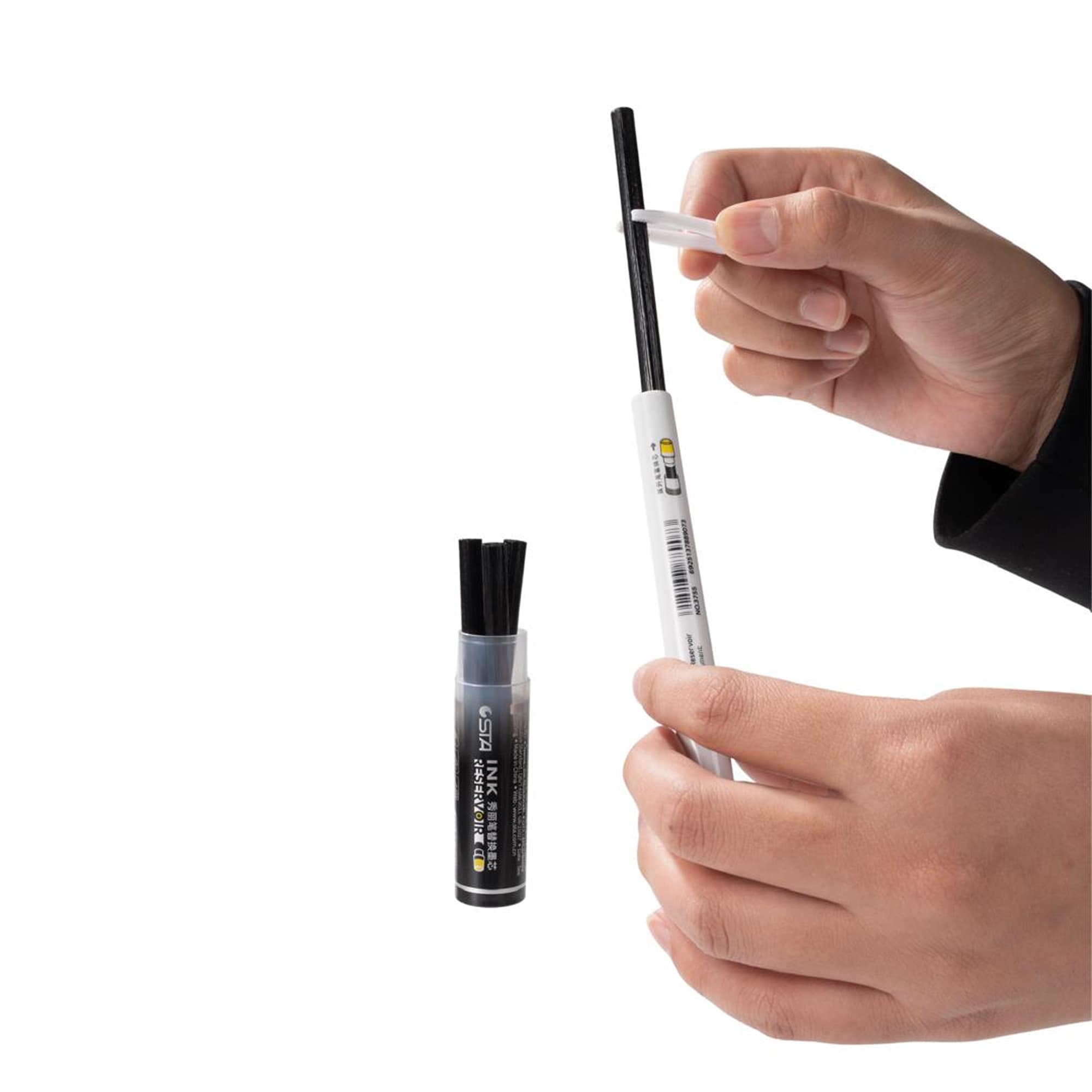 Hands inserting a refill cartridge into a white brush pen, beside the ink tube Image