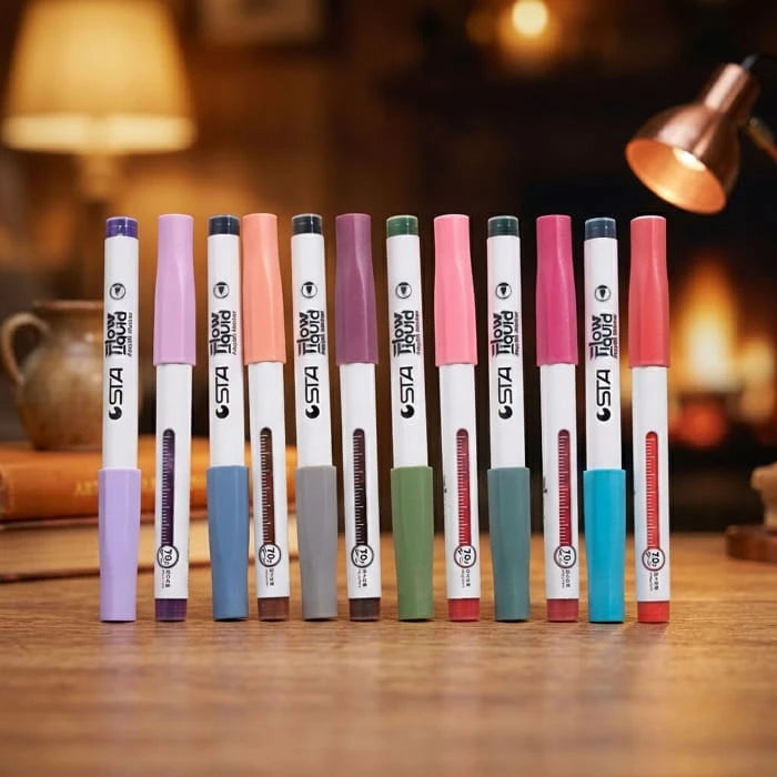 Twelve acrylic brush markers lined up in a row on a wooden table under warm light